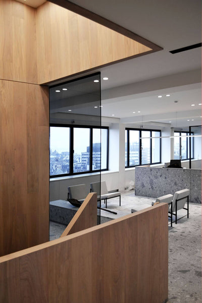 The top of a wooden staircase leading into an office with modern stone accents.