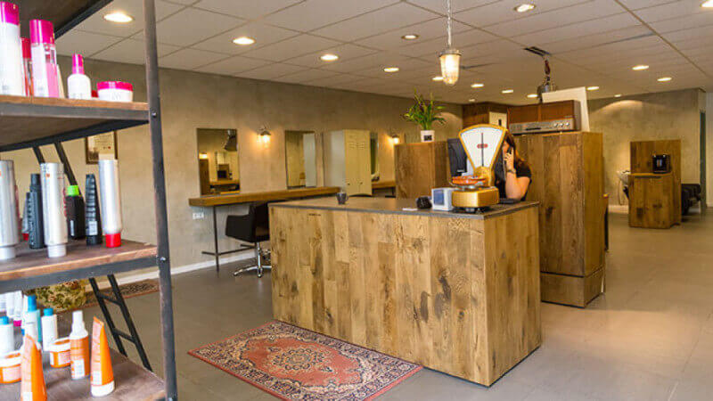 A wide view of the interior of a barbershop with multiple wooden fixtures.