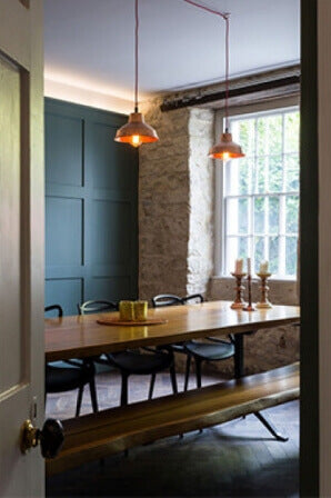 Teal paneled accent wall in a dining room with long live edge wood table.