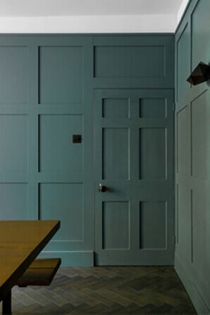 Teal paneled accent wall in dining room with herringbone wood floors.