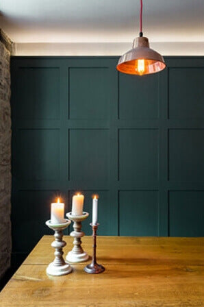 Live edge dining table with candles on it and teal walls behind.