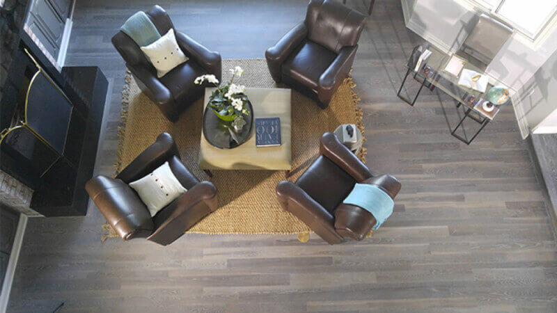A fumed hardwood floor in a living room with chairs around it.