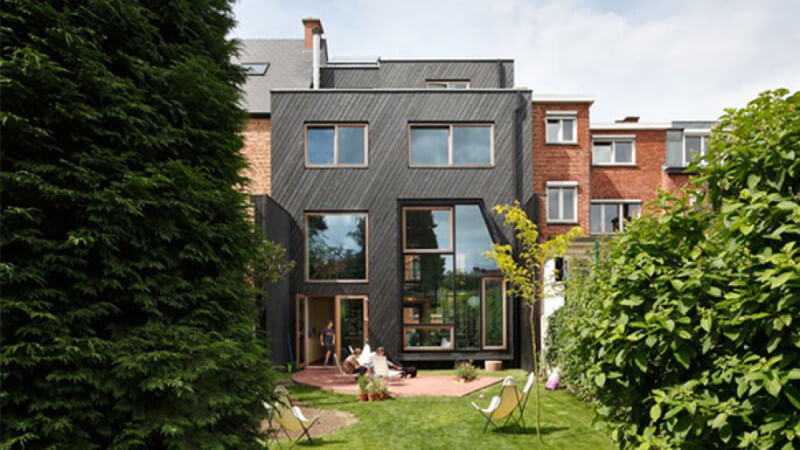 The entrance to a masterfully designed house with large windows across the front and beautiful exterior wood siding running at an angle.