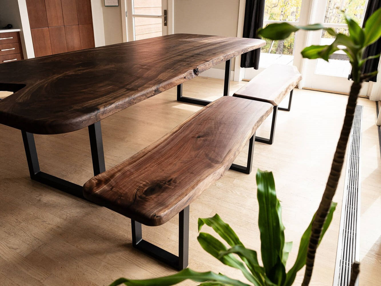 A large claro walnut dining table with two benches.