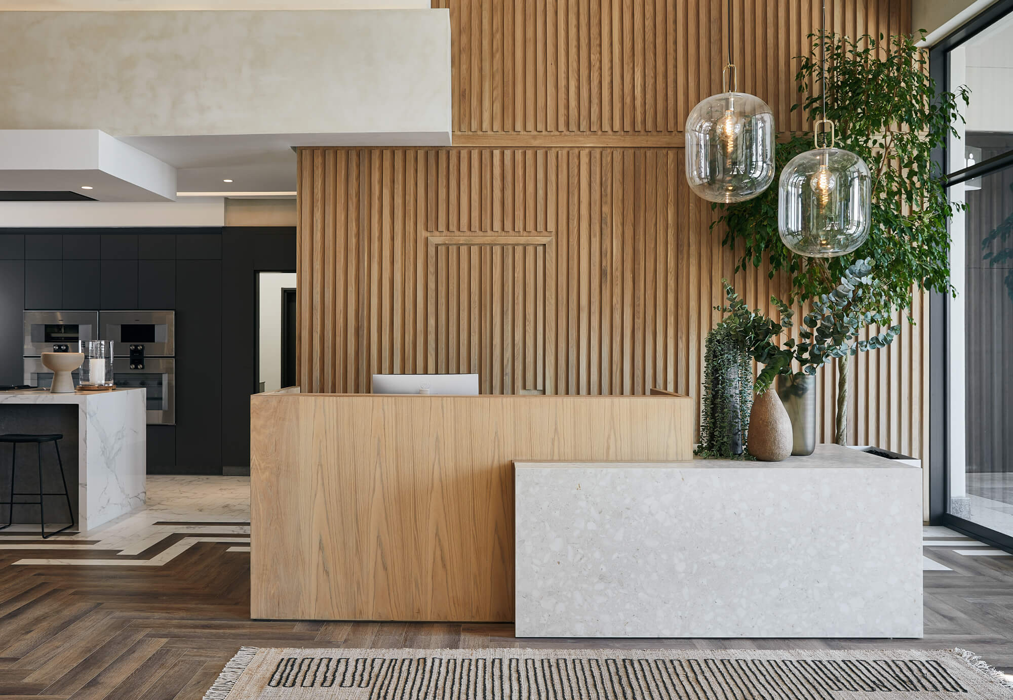 The entrance to a residential development office featuring a wood slatted wall and white oak reception desk finished with Oil Plus 2C in the colour Mist.