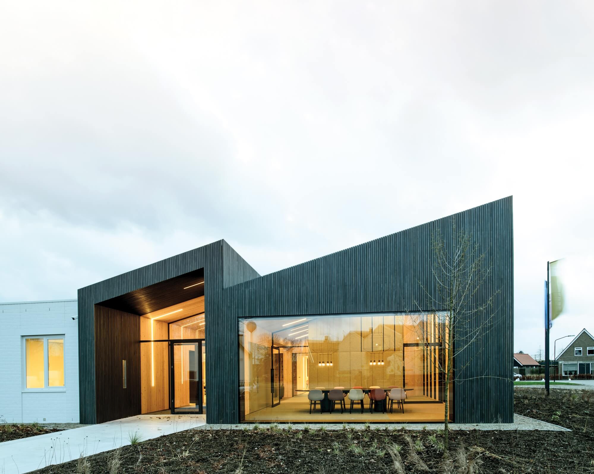 Modern office space with slanted roof, wood siding and large glass windows.