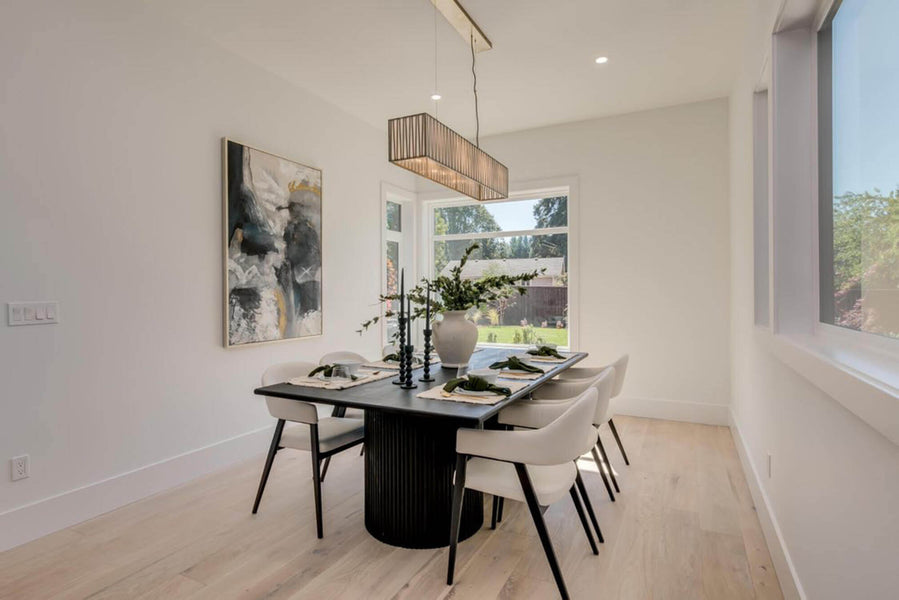 A large black fluted white oak dining table is set with six place settings. A large rectangular light hangs above it.