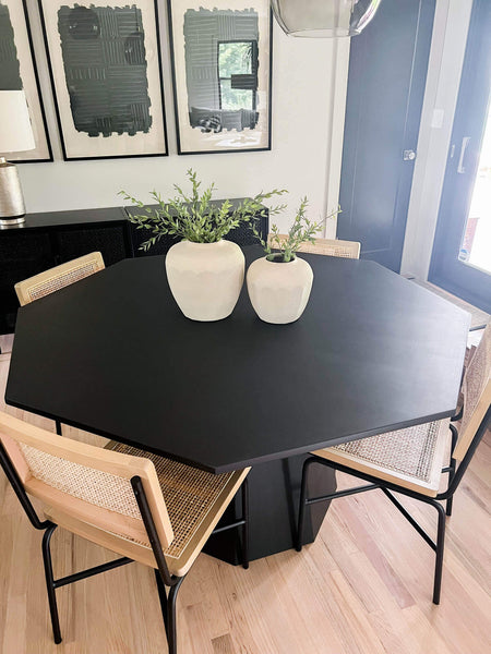 The top of a black maple octagon shaped dining table with two decorative vases on it.