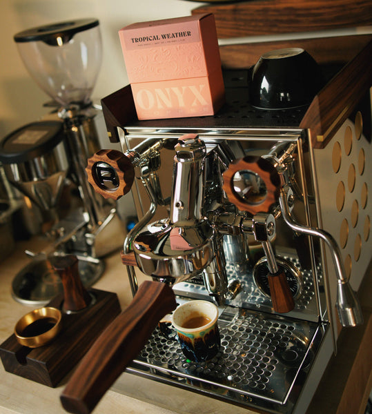 Espresso machine with walnut wood accents in action.