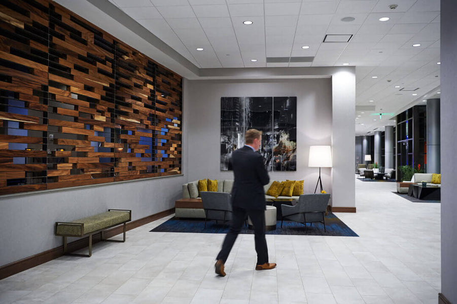 Man walking through hotel lobby with wood accent wall to his left.