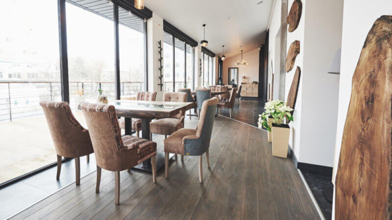 A rustic restaurant dining area with wood floors and wood cookie artwork on the walls.