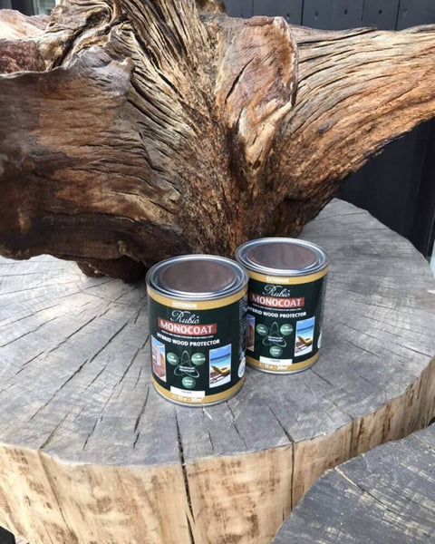 Rubio Monocoat Hybrid Wood Protector cans sitting on a tree stump outside.