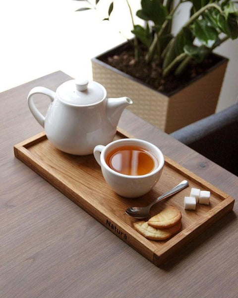 A serving tray with tea and cookies sitting on a matte finished wood table in a restaurant.