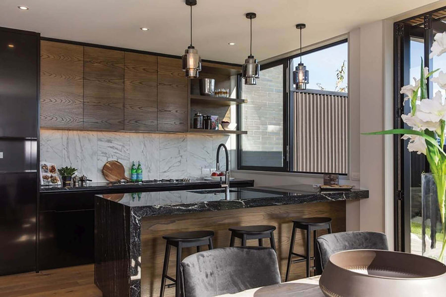 Warm kitchen designed with brown wood cabinets and dark marbled counters.