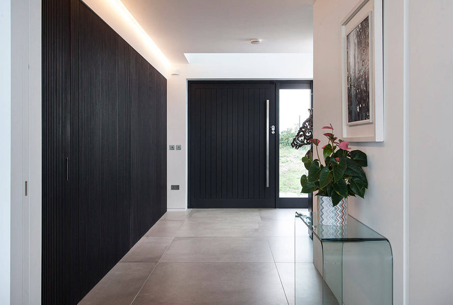 Looking at the black slatted wall from an opposite angle with a view of the entrance to the home.
