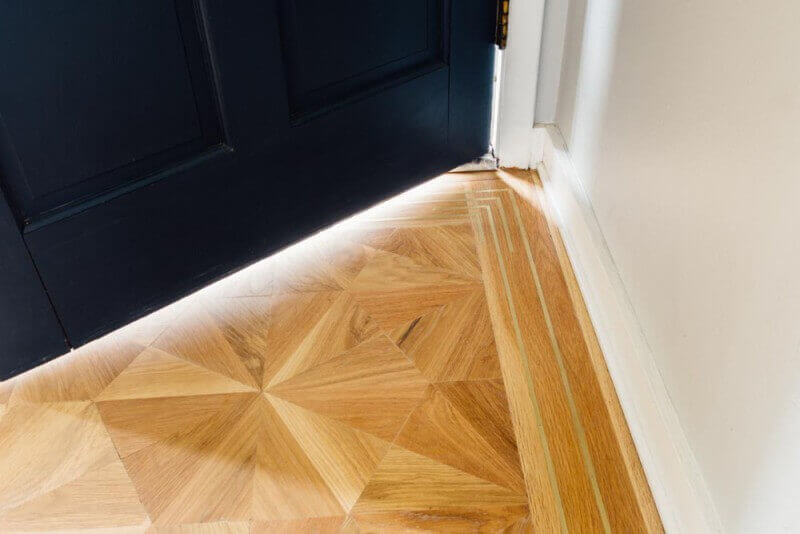 Detail of a solid white oak parquet inlay floor with brass border.