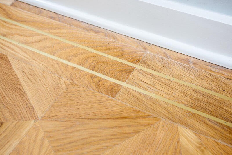 Detail image of a brass border inlay on a white oak parquet floor.