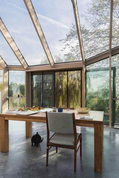 Table in glass sun room with wood beams.