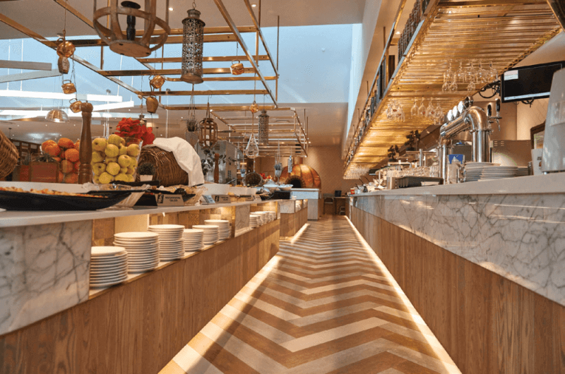 A matte finish herringbone floor inside a fine buffet style restaurant with matte finish cabinetry.