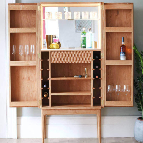 Open oak wood liquor cabinet with carved design.