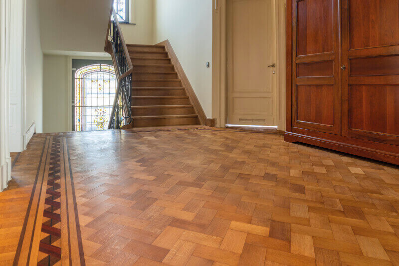 Classic hardwood floor with herringbone pattern and border inlay.