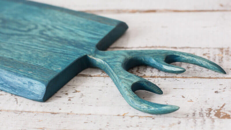 A greenish blue wood serving tray with antlers carved out of the wood.