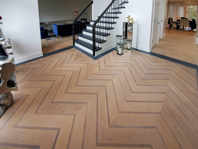 Entry way with solid white oak hardwood chevron floor with walnut accents and a dark border, finished with Rubio Monocoat products.