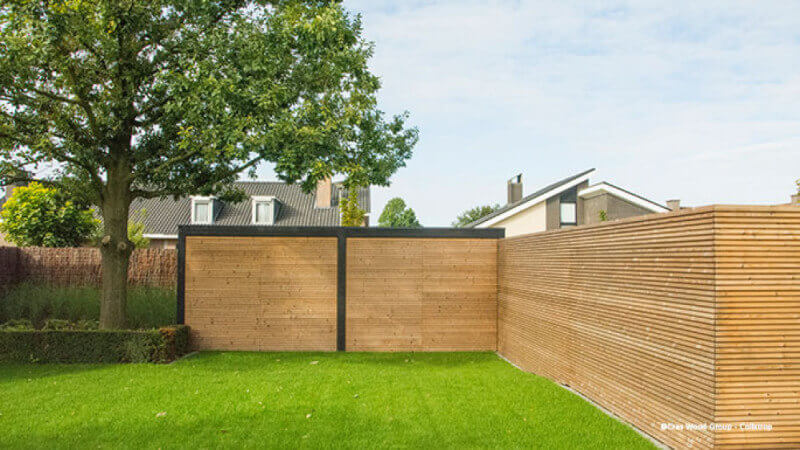 A a green yard with a fence finished using Rubio Monocoat exterior oil finish.