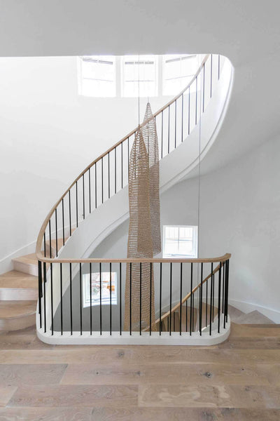 Winding staircase with hardwood treads and decor hanging down beside the stairs.