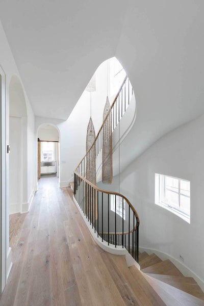 A wood staircase leads to a hallway with hardwood flooring.