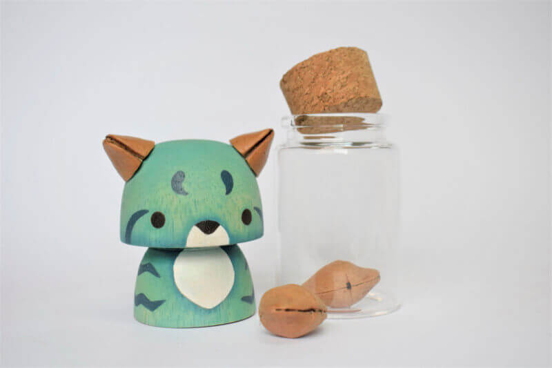 Small wooden animal sculpture next to a glass bottle