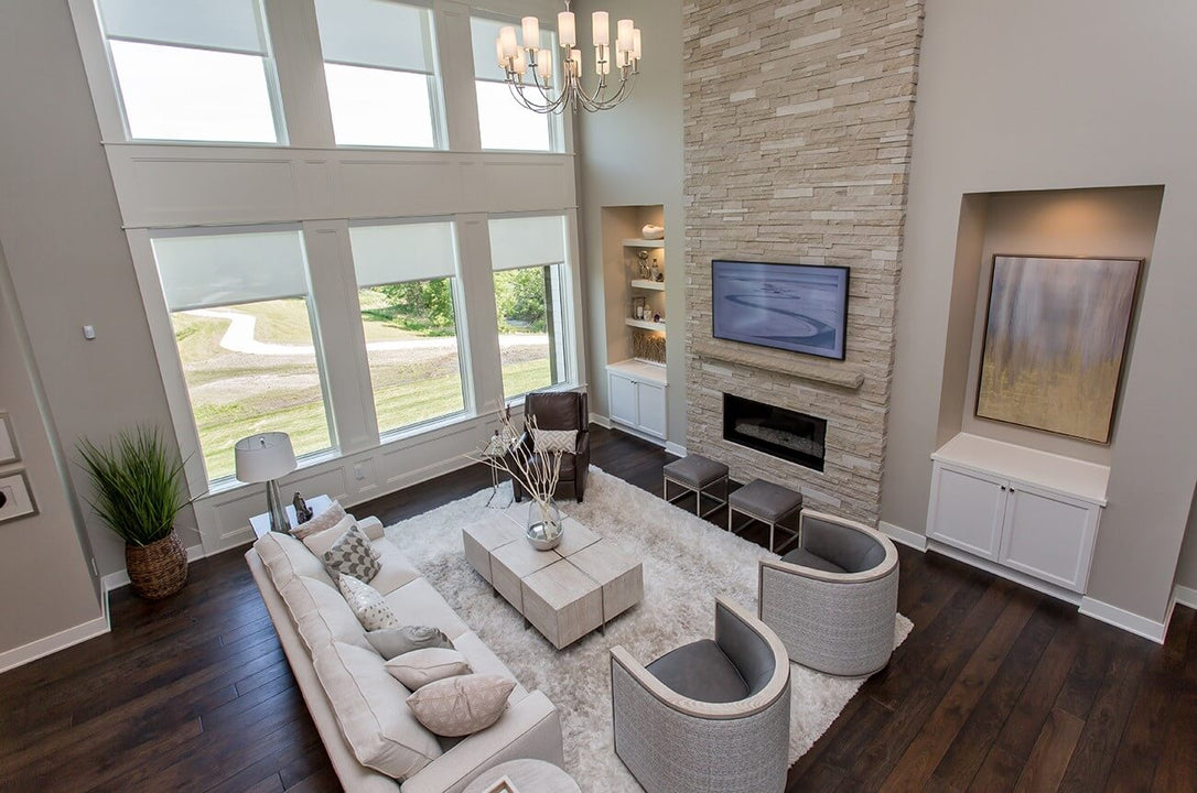 Dark hardwood flooring in a living room with tall windows, a fireplace, built in cabinets, and a seating area.