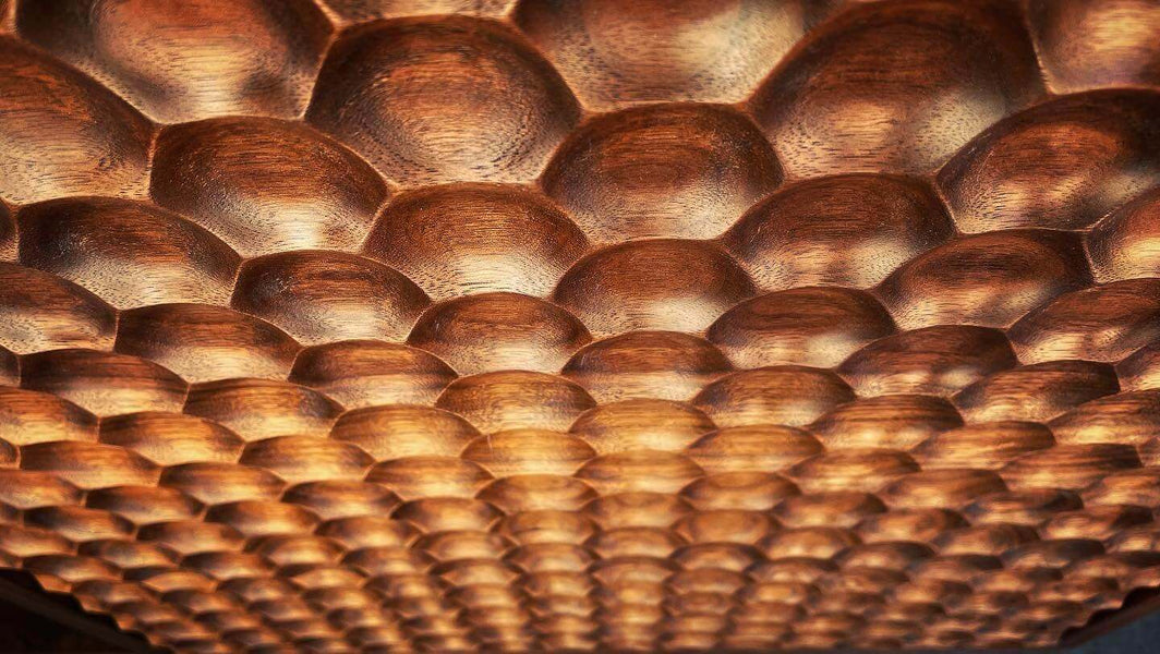 Repeating honeycomb pattern milled into walnut wood.