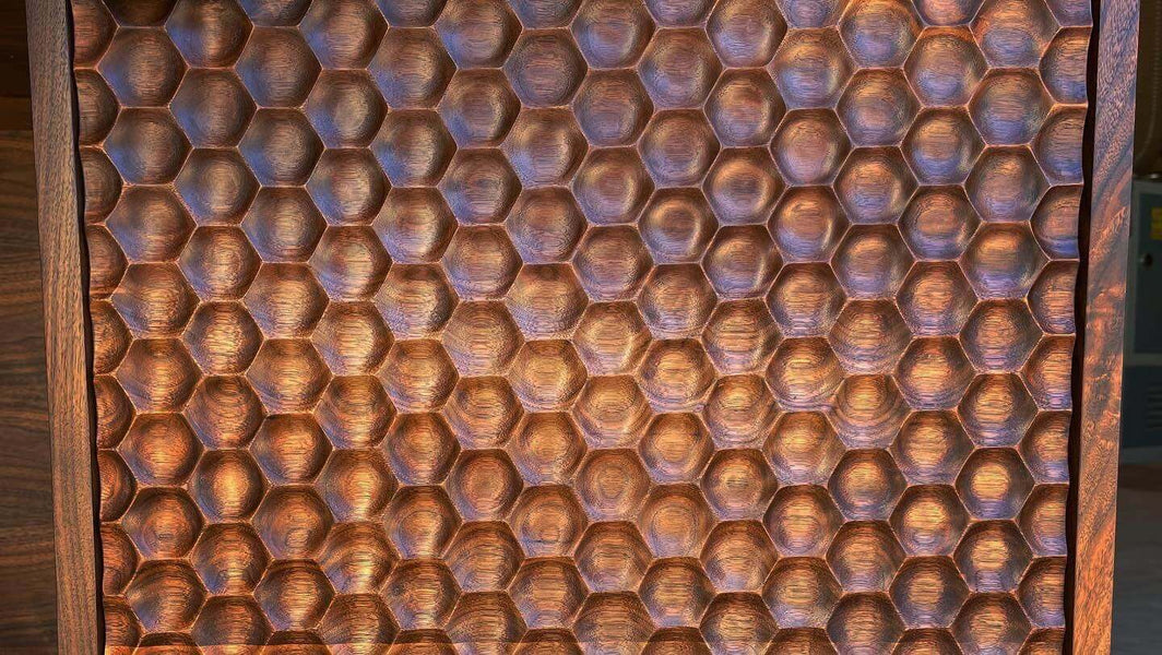 Front view of repeating honeycomb pattern machined with a CNC into walnut wood.
