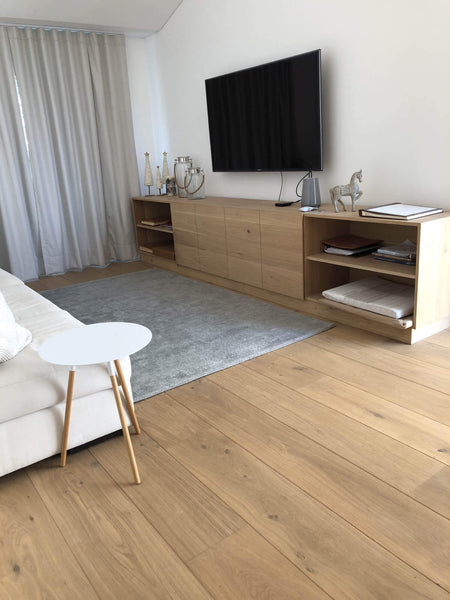 Living room with wide plank white oak flooring and matching entertainment center.