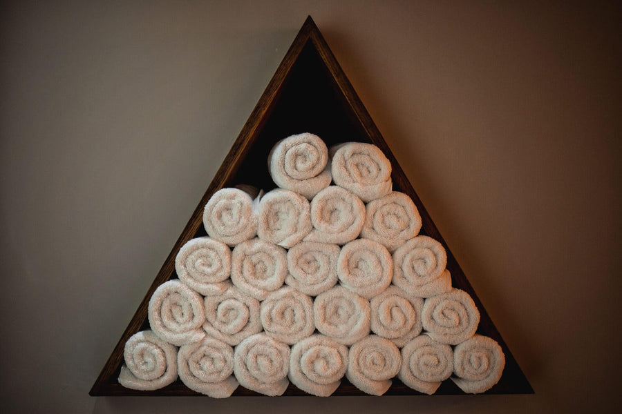 Triangular storage shelves filled with white towels.