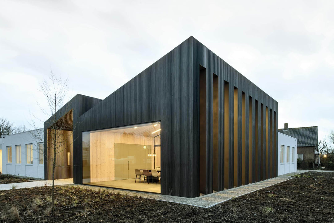 Small sized modern office building with slanted roof, wood siding and large glass windows.