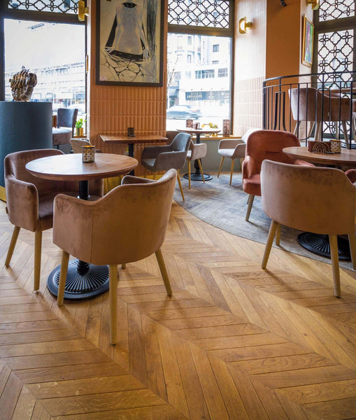 Restaurant tables on an oak chevron floor.