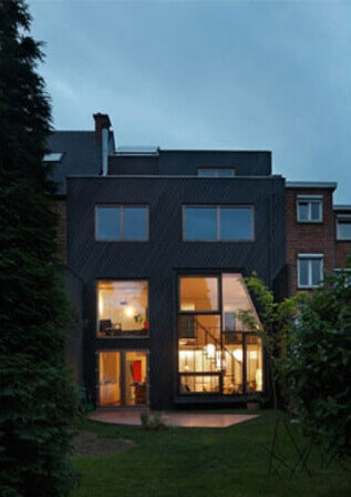 The outside of a house at dusk with the lights on inside.