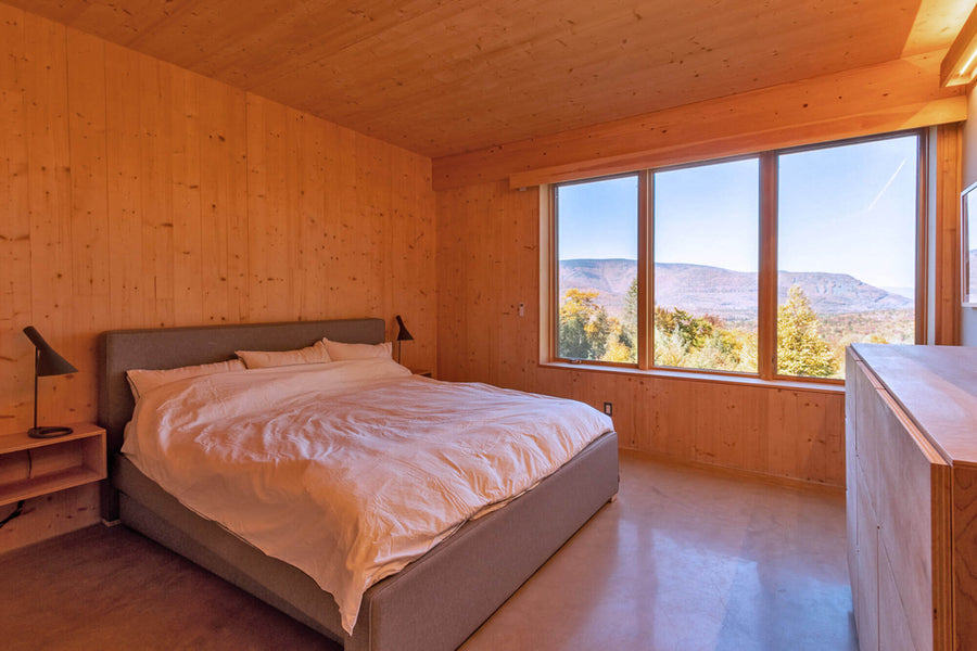 A modern bedroom with wood planed walls and a view of the fall landscape.