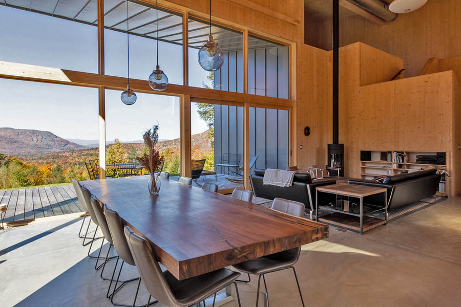 Acacia dining table and large open windows looking out over a mountainous landscape.