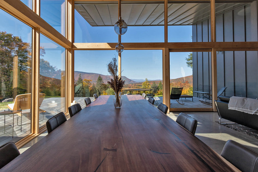 A view of the large acacia dining table looking out towards two large walls of windows.