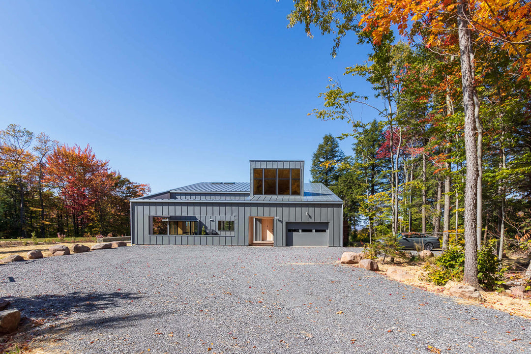 The backside of the Berghaus Hunter contemporary lodge home. Windows, a garage door and a path leading to the front entrance is pictured.