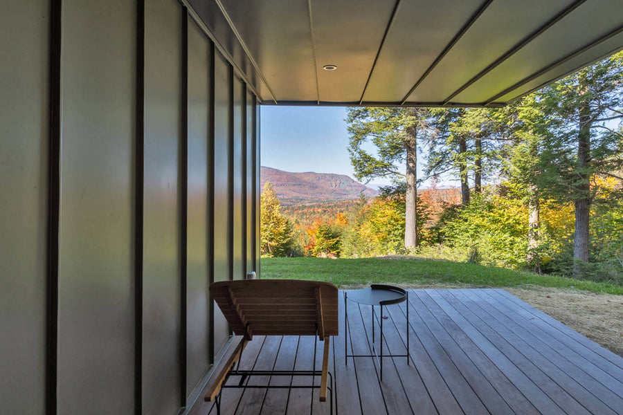 Wooden patio and lounge chair overlooking a beautiful fall mountainous landscape.