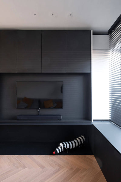 Corner of living room with light colored white oak herringbone flooring and dark colored built-ins.