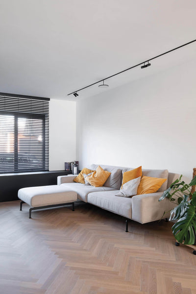 White oak herringbone flooring with gray couch in a modern minimal home.