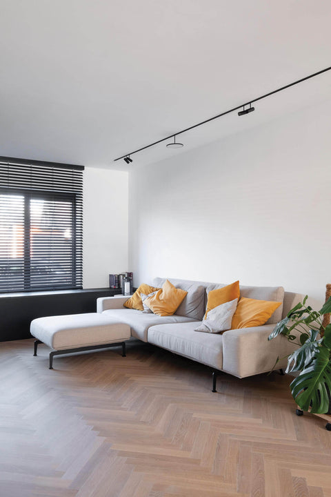White oak herringbone flooring with gray couch in a modern minimal home.