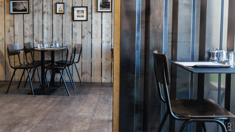 Wooden flooring and walls inside of a shipping container restaurant.