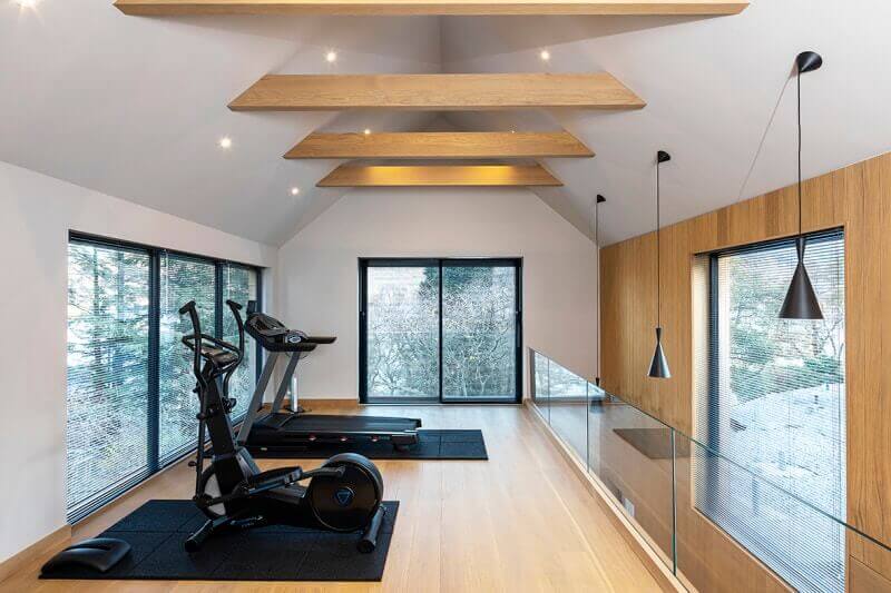 Fitness room with hardwood flooring, a wood accent wall, and faux wood beams.