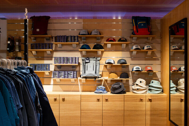 A wall in a store lined with wood displays that show hats, backpacks, and other items for sale.